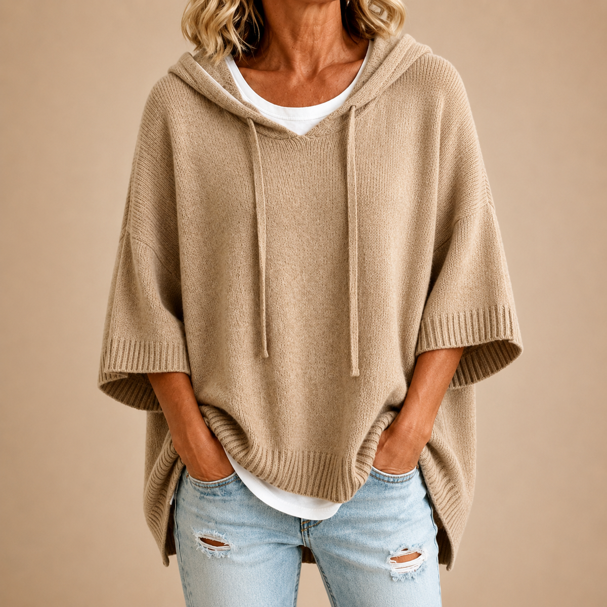 Beiger Strickponcho mit Kapuze und Kordelzug am V-Ausschnitt, Vorderansicht.
