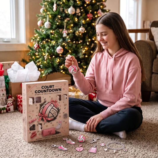 Lächelndes Mädchen im rosa Hoodie sitzt vor dem Weihnachtsbaum und hält einen Volleyball-Anhänger neben der 1