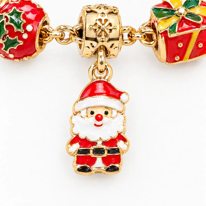 Nahaufnahme eines goldfarbenen Weihnachtsmann-Anhängers aus Emaille, daneben ein Stechpalmen-Charm und ein rotes Geschenk-Charm am Armband. 3