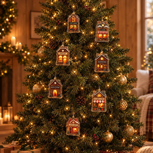 Sieben kleine Häuschen-Anhänger mit beleuchteten Fenstern hängen an einem festlich geschmückten Weihnachtsbaum mit Lichterkette, Zapfen und goldenen Kugeln. 1