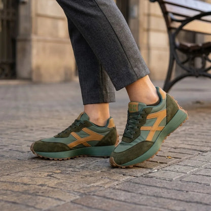 Grüne Sneaker mit orangebraunen Streifen, getragen zu grauer Hose auf Kopfsteinpflaster 12