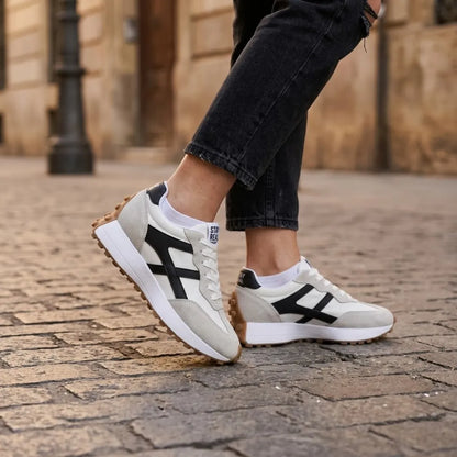 Sneaker an den Füßen einer Frau in schwarzer Jeans auf Kopfsteinpflaster 22