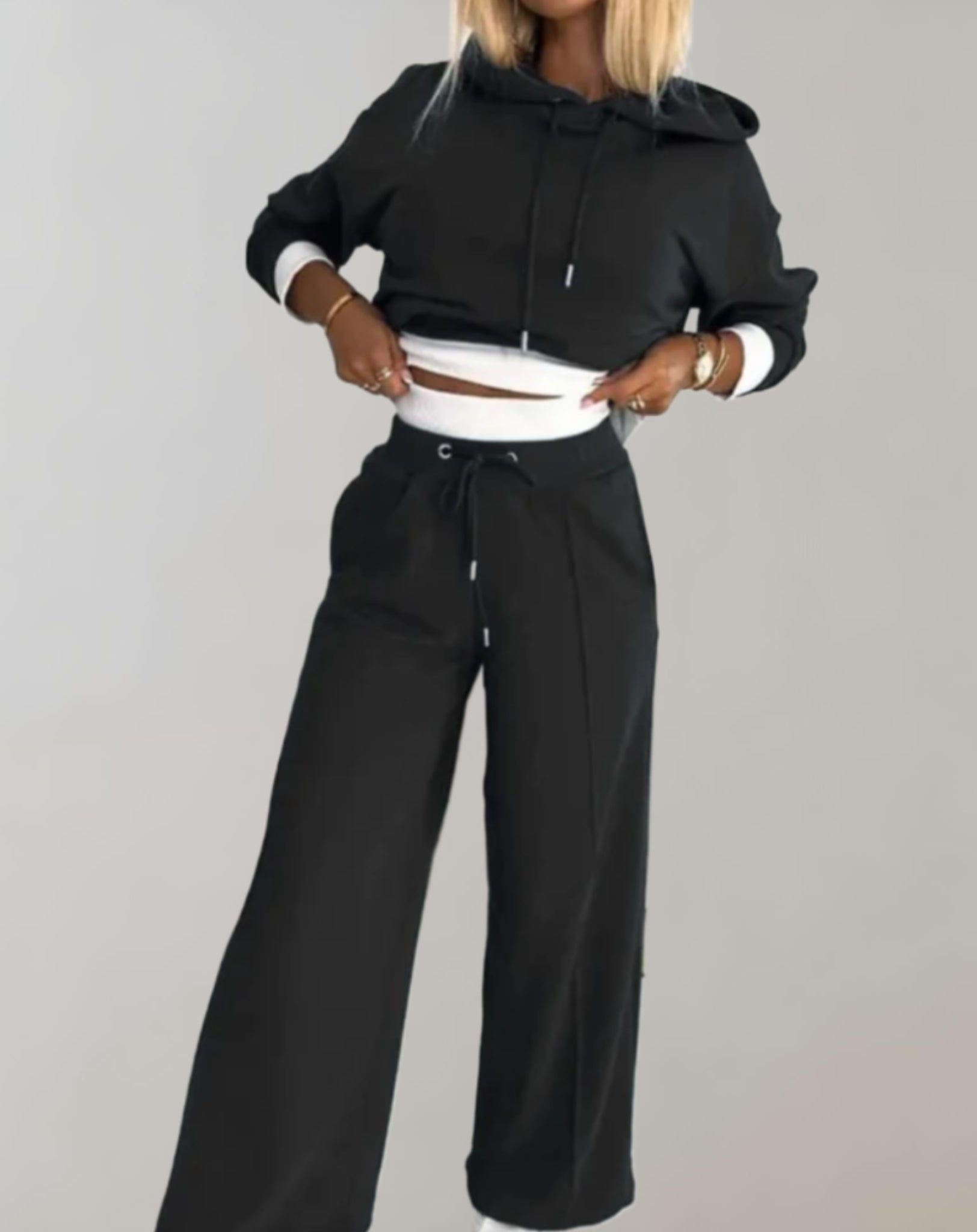 Frau in schwarzem Jogginganzug mit Kapuze, weite Hose, Freizeitmode, bequemes Outfit.