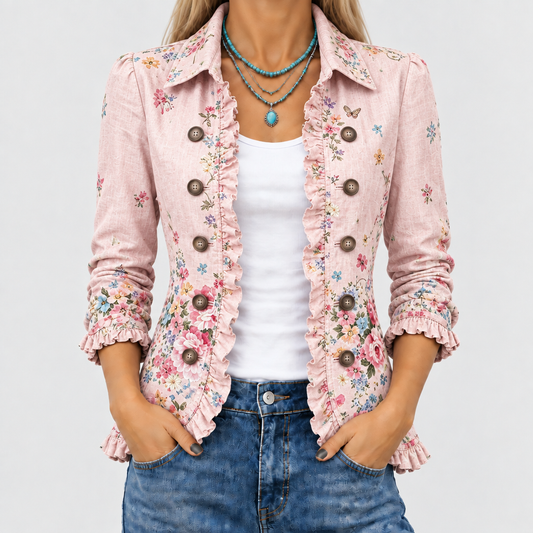 Nahaufnahme der rosa Blumenjacke am Oberkörper: Rüschenkanten, Knopfreihen und Kragen, kombiniert mit weißem Top, Jeans und türkisfarbener Halskette. 1