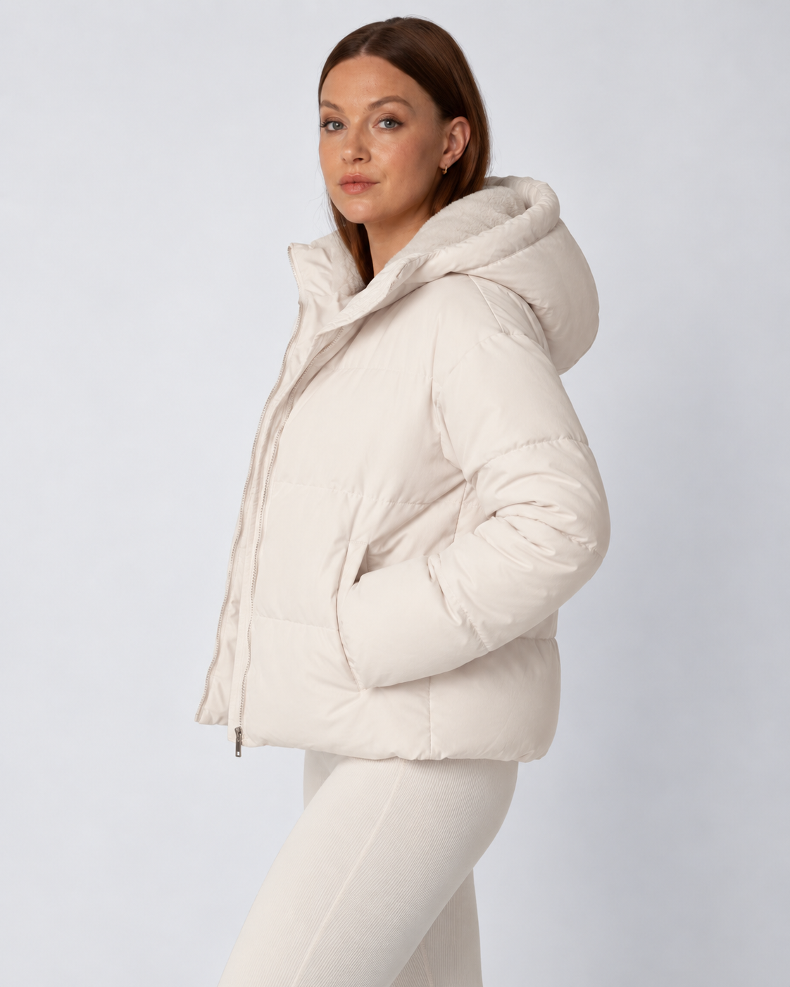 Seitenansicht der cremeweißen Steppjacke mit aufgesetzter Kapuze und Fleecefutter, Hände in den Taschen 3