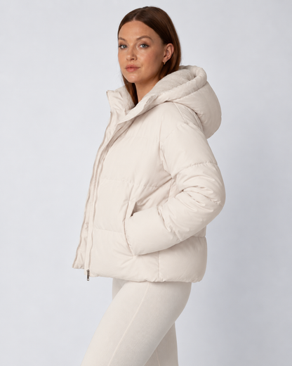Seitenansicht der cremeweißen Steppjacke mit aufgesetzter Kapuze und Fleecefutter, Hände in den Taschen 3