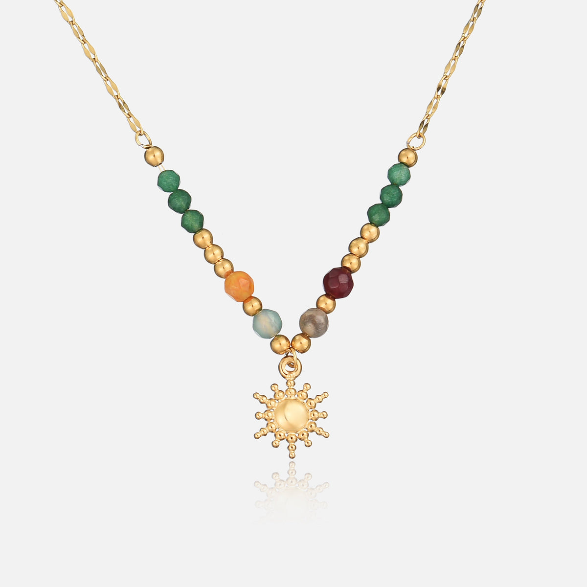 Goldene Kette mit grünen, orangefarbenen und roten Perlen und kleinem Sonnenanhänger, frontal auf hellem Hintergrund 1
