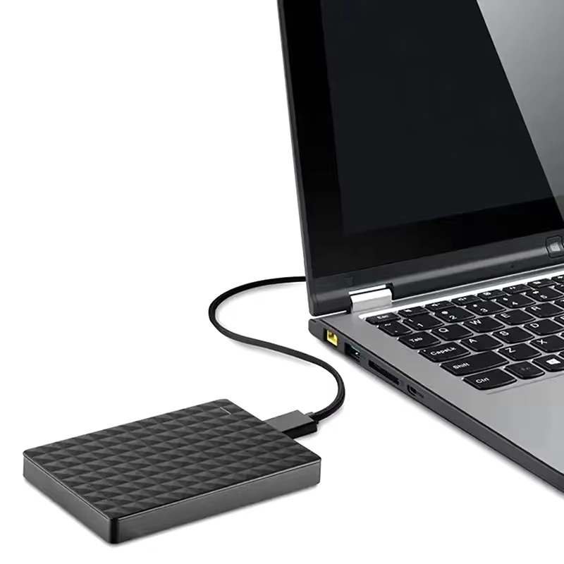Festplatte neben einem aufgeklappten Laptop, über ein geschwungenes schwarzes Kabel mit dessen USB-Anschluss verbunden 5