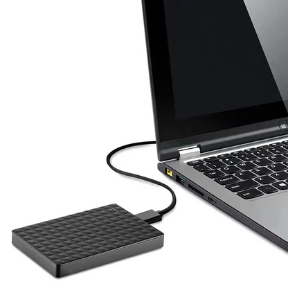 Festplatte neben einem aufgeklappten Laptop, über ein geschwungenes schwarzes Kabel mit dessen USB-Anschluss verbunden 5
