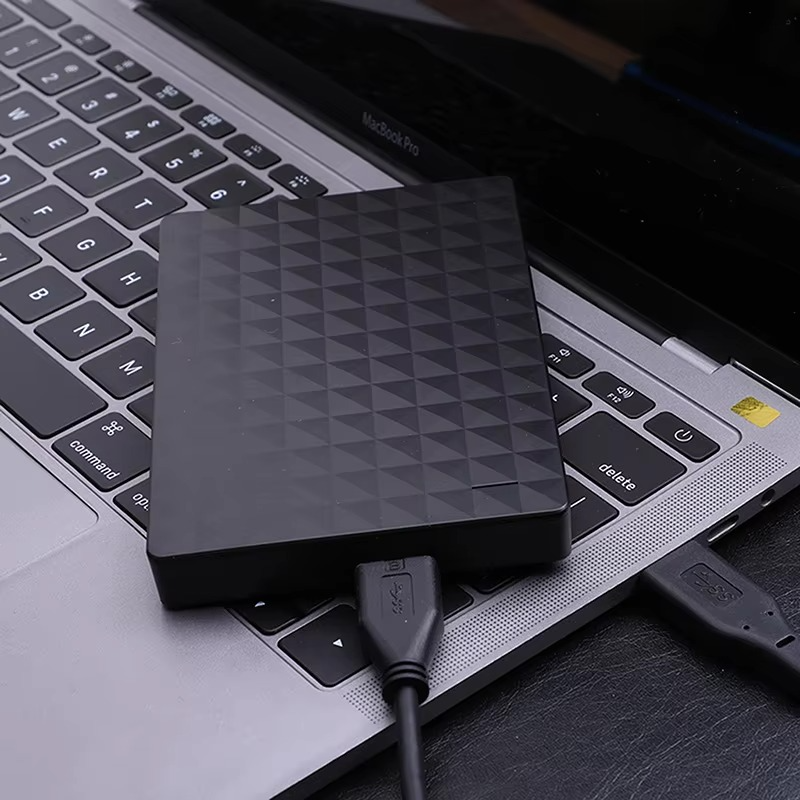 Schwarze tragbare externe Festplatte auf der Tastatur eines Laptops mit angeschlossenem USB-Kabel