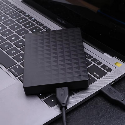 Schwarze tragbare externe Festplatte auf der Tastatur eines Laptops mit angeschlossenem USB-Kabel
