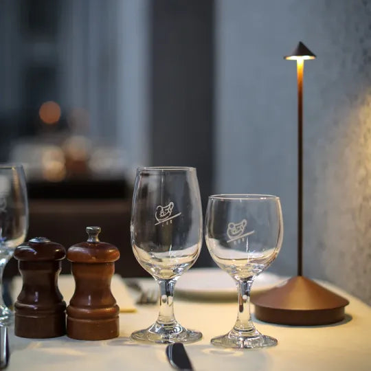 Braune Tischlampe leuchtet warm auf einem gedeckten Tisch neben Weingläsern sowie Salz- und Pfeffermühle aus Holz 23