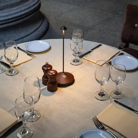 Lampe in Rosttönen auf rundem Tisch zwischen Salz- und Pfeffermühle, Gläsern und Tellern 5