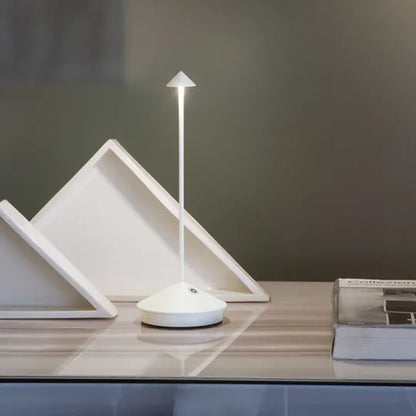 Weiße Lampe auf einer glänzenden Ablage neben dreieckigen weißen Aufstellern und einem Buch 8