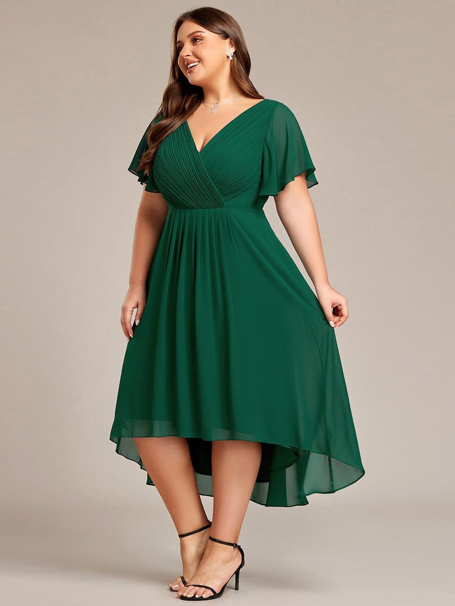 Curvy Model im dunkelgrünen Kleid, seitlich gedreht, hält den Rock leicht an und zeigt den fließenden Hoch-Tief-Saum. 39