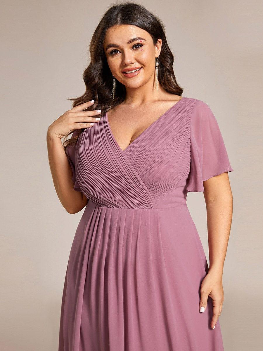 Detailaufnahme des gerafften, überkreuzten Oberteils in Altrosa mit Flatterärmel, getragen von einem Plus-Size-Model mit langen Ohrringen. 65
