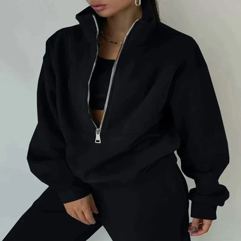 Frau in schwarzem Reißverschluss-Sweatshirt und Hose, modisch, lässig, Streetwear-Look.