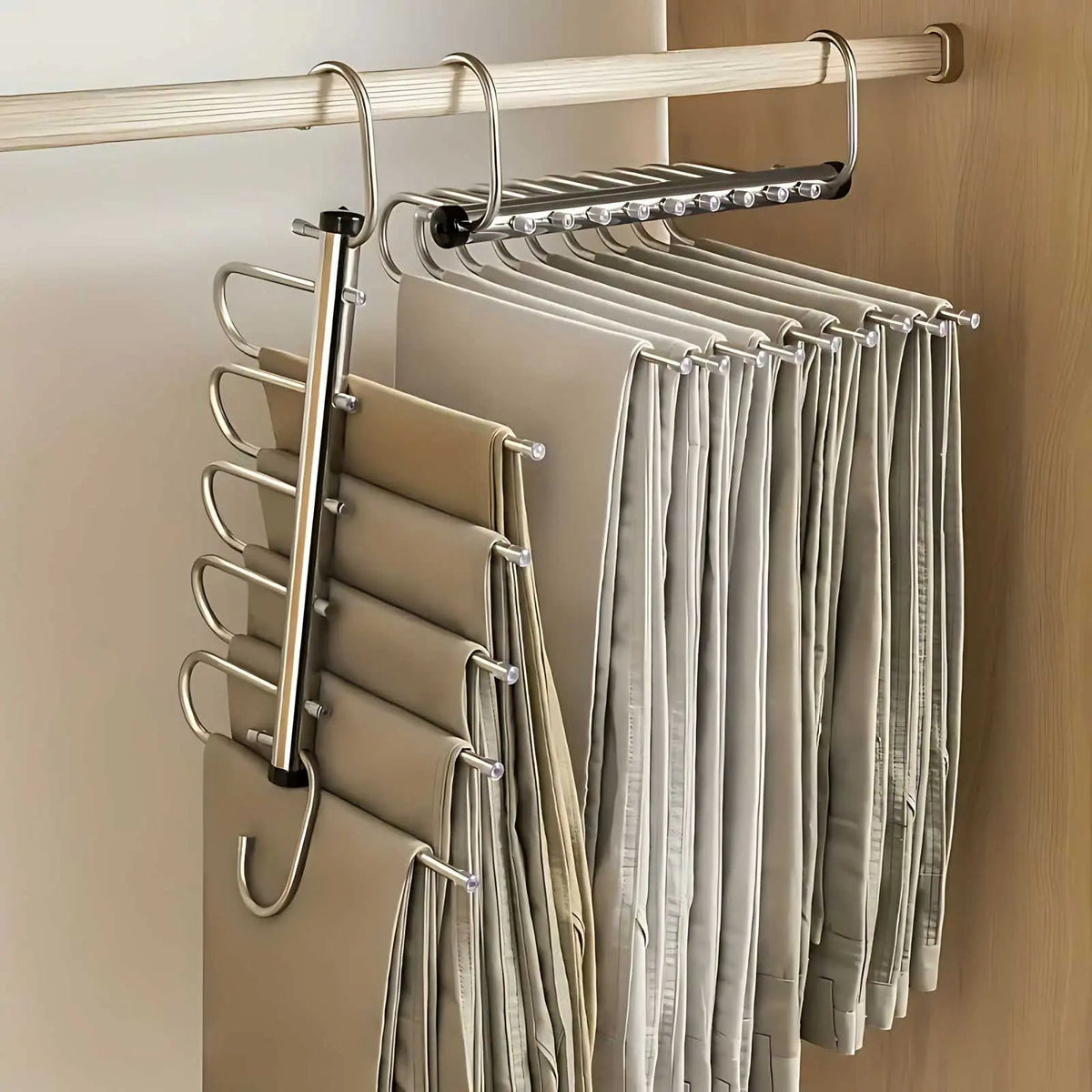 Zwei Edelstahl-Hosenbügel an einer Kleiderstange, einer senkrecht ausgeklappt und einer waagerecht, beide mit vielen Hosen behängt. 1