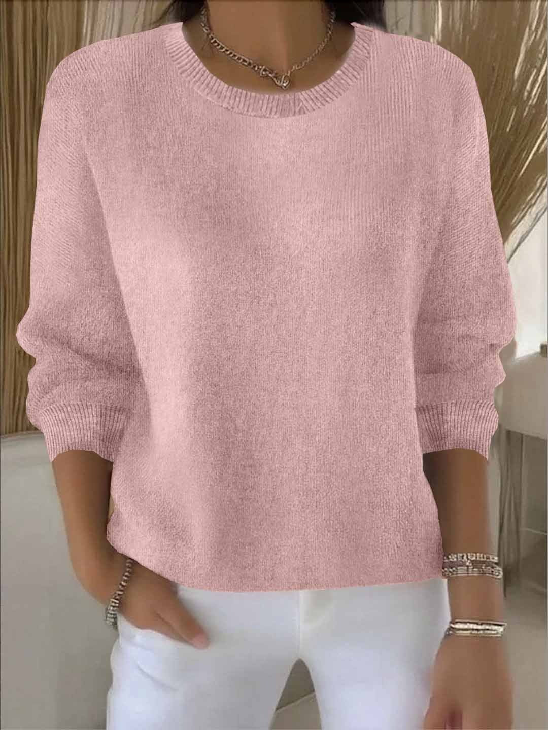 Frontansicht des Rundhals-Pullovers in Rosa, getragen zu weißer Hose mit Silberschmuck 2