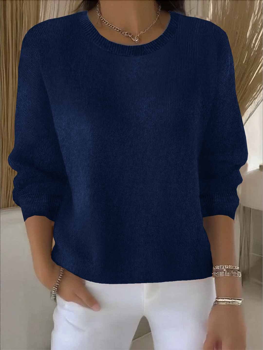 Frau trägt den Rundhals-Pullover in Dunkelblau zu weißer Hose mit Halskette 9