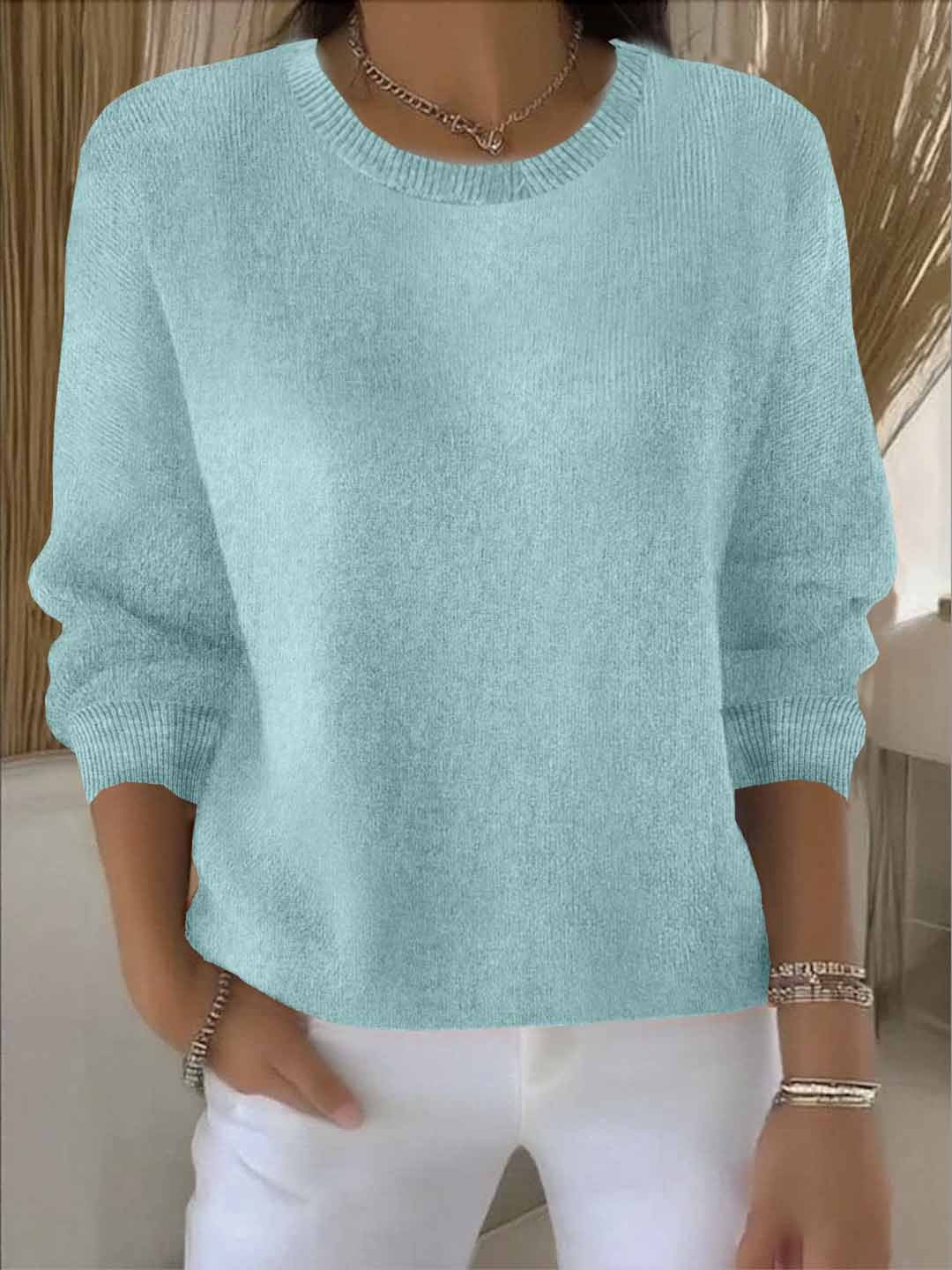 Frontansicht des Strickpullovers in Hellblau-Mint, kombiniert mit weißer Hose und Armbändern 10