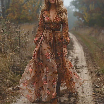 Frau im fließenden Maxikleid mit rosa-orangem Blumenmuster, V-Ausschnitt und dunklem Gürtel auf einem herbstlichen Weg 4