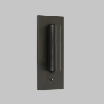 Lampe in dunklem Bronzeton mit eingeklapptem Strahlerrohr, schräg von der Seite vor grauer Wand 2