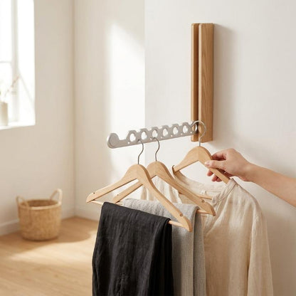 Heller Holzhaken mit silbernem Arm an der Wand, an dem eine Hand einen Bügel mit Leinenhemd aufhängt. 3