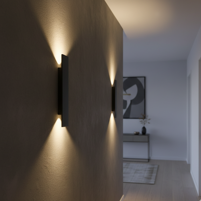 Zwei schwarze Wandleuchten an einer Flurwand im Innenraum, mit warmem Licht nach oben und unten.