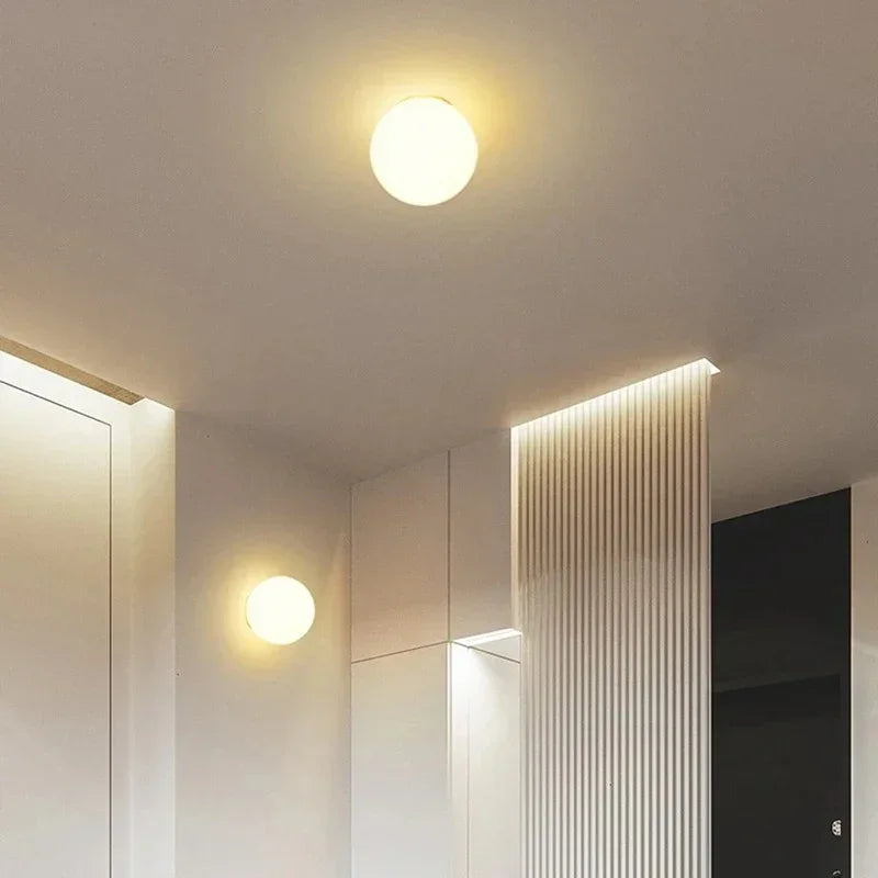 Zwei Kugelleuchten, eine an der Decke, eine an der Wand, in einem Flur mit Lichtleisten 10