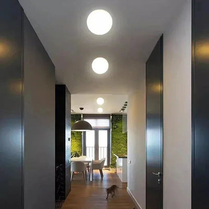 Zwei leuchtende Kugelleuchten an der Decke eines langen, dunkel gehaltenen Flurs mit Blick zum Esstisch 1