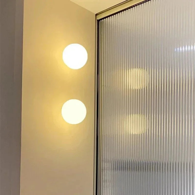 Zwei übereinander an der Wand montierte Kugelleuchten neben einer geriffelten Glastür 14