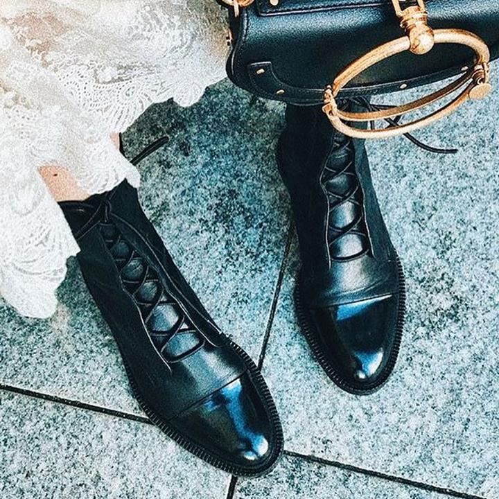 Schwarze Lederstiefel mit Schnürung, Damenmode, elegante Schuhe, auf grauem Boden.