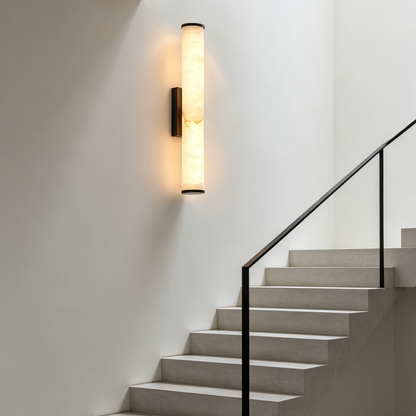 Wandleuchte mit Marmorschirm und dunkler Halterung an einer weißen Wand über einer modernen Treppe
