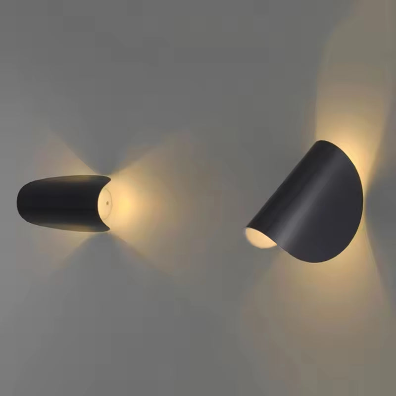 Zwei schwarze Wandleuchten in unterschiedlicher Position, die den verstellbaren Lichtkegel an grauer Wand zeigen.