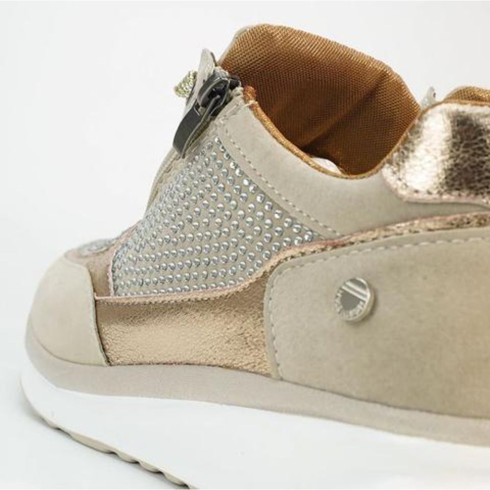 Detailansicht der Ferse mit Reißverschluss, Strasssteinen, goldfarbenen Einsätzen und orangefarbenem Innenfutter am beigen Schuh.