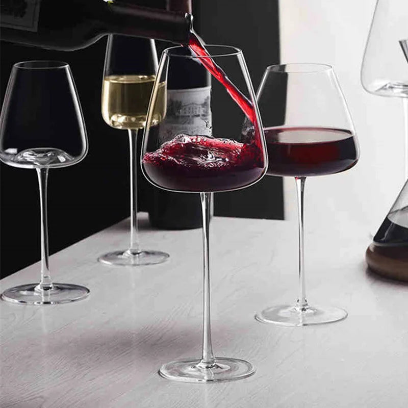 Rotwein wird aus einer Flasche in ein Glas gegossen, daneben Gläser mit Weißwein und Rotwein 2