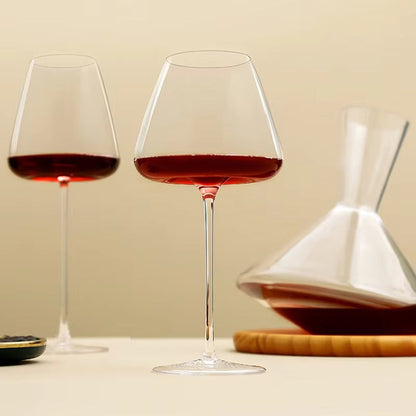 Zwei Gläser mit Rotwein vor beigem Hintergrund, rechts eine kegelförmige Karaffe auf Holzuntersetzer 8