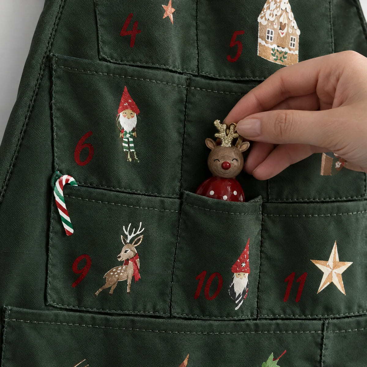 Nahaufnahme einiger Taschen mit aufgedruckten Zahlen und Motiven, eine Hand zieht eine kleine Rentierfigur aus einem Fach. 3
