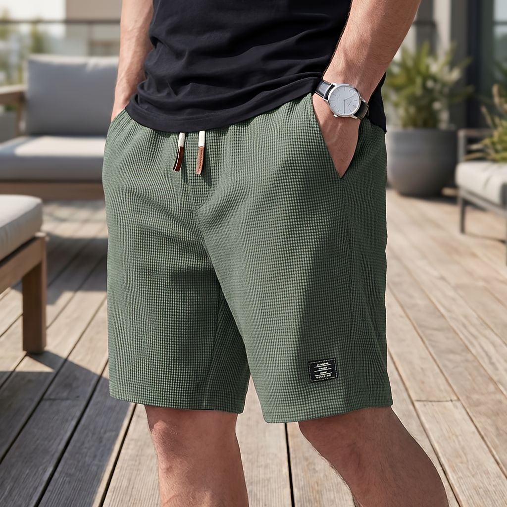 Model trägt die Shorts in Olivgrün mit Waffelstruktur und hellem Kordelzug mit braunen Enden, Hand in der Seitentasche. 5