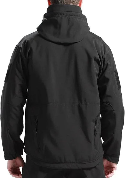 Rückansicht der schwarzen Jacke an einem Mann, mit Kapuze, Klettflächen an den Ärmeln und zwei Reißverschlusstaschen unten. 4