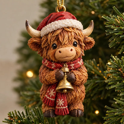 Nahaufnahme einer Highland-Rind-Figur mit roter Weihnachtsmütze, gemustertem Schal und goldener Glocke, an einem Tannenzweig hängend. 3