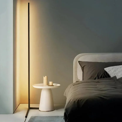 Leuchtende schwarze Stehlampe neben einem hellen Beistelltisch und einem Bett mit dunkler Bettwäsche 1
