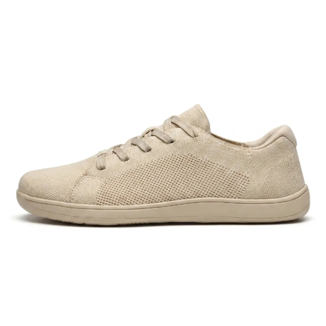 Beiger Mesh-Sneaker in der Seitenansicht mit flacher Sohle vor weißem Hintergrund.