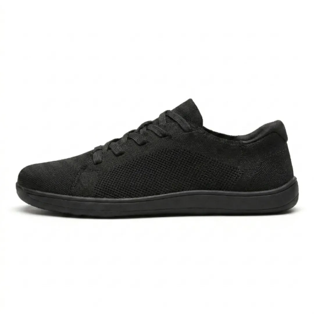 Schwarzer Mesh-Sneaker mit schwarzer flacher Sohle in der Seitenansicht vor weißem Hintergrund. 10