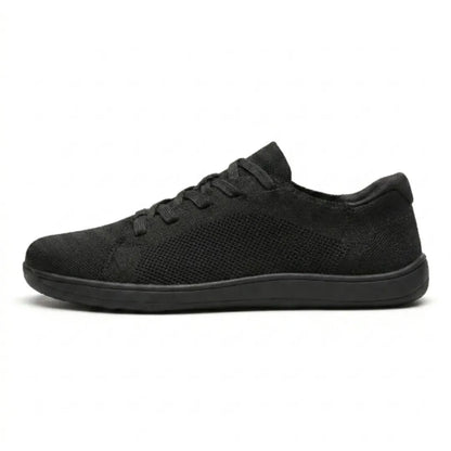 Schwarzer Mesh-Sneaker mit schwarzer flacher Sohle in der Seitenansicht vor weißem Hintergrund. 10