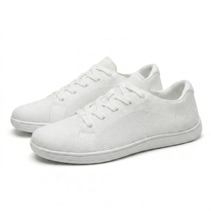 Paar weißer Barfuß-Sneaker aus Mesh mit Schnürung und flacher weißer Sohle, schräg von der Seite auf hellem Hintergrund. 43