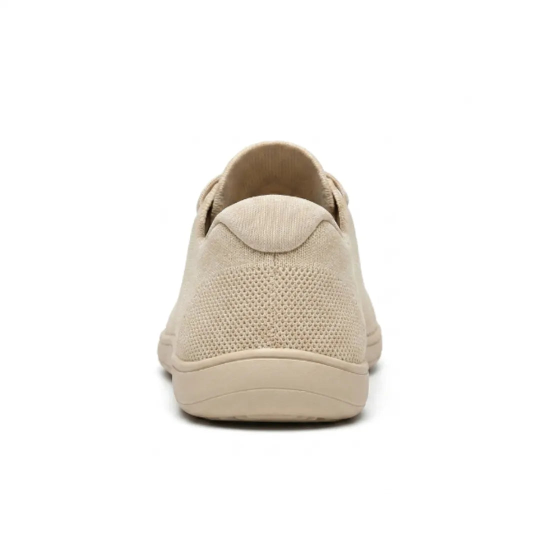 Beiger Sneaker von hinten mit Fersenkappe, perforiertem Gewebe und flacher, breiter Sohle.
