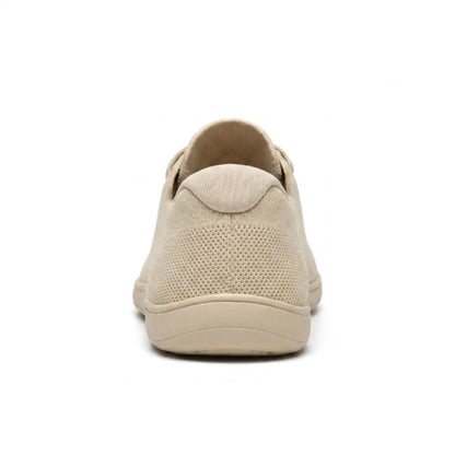 Beiger Sneaker von hinten mit Fersenkappe, perforiertem Gewebe und flacher, breiter Sohle.