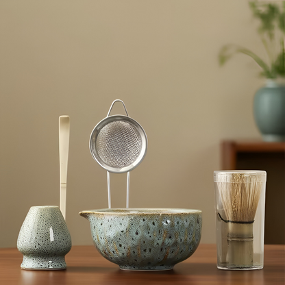 5-teiliges Matcha-Set mit gesprenkelter Keramikschale, Bambuszubehör und Klarsichtdose vor beigem Hintergrund